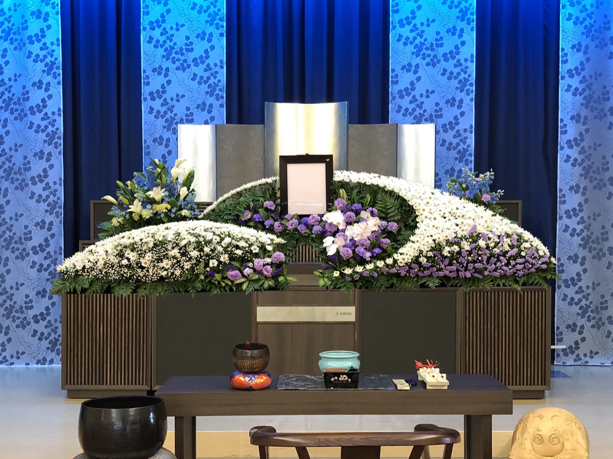 青い幕を背景にした白菊と紫の祭壇
